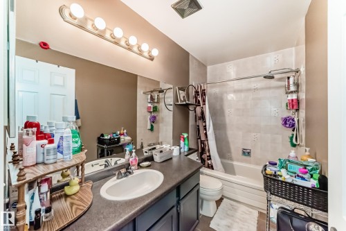 Bathroom featuring a single vanity with an integrated sink, a large wall-mounted mirror, a tub-shower combination with tiled walls, and recessed overhead lighting - 9845 184 Street, Edmonton, AB - Indoor Photo Showing Bathroom