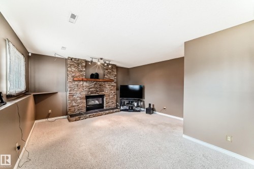 Stone-clad fireplace with a wood mantel and integrated hearth - 9845 184 Street, Edmonton, AB - Indoor With Fireplace