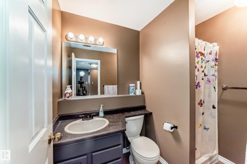 Bathroom featuring a vanity with an oval sink, dark countertop, and a vanity mirror with a four-bulb light fixture - 9845 184 Street, Edmonton, AB - Indoor Photo Showing Bathroom