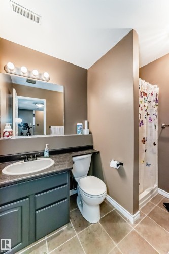 Bathroom featuring a vanity with a dark countertop and integrated sink, a commode, and a shower area with a shower curtain - 9845 184 Street, Edmonton, AB - Indoor Photo Showing Bathroom