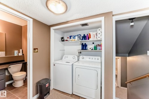 Dedicated laundry closet featuring a white washer and dryer, built-in shelving, and overhead flush mount lighting - 9845 184 Street, Edmonton, AB - Indoor Photo Showing Laundry Room
