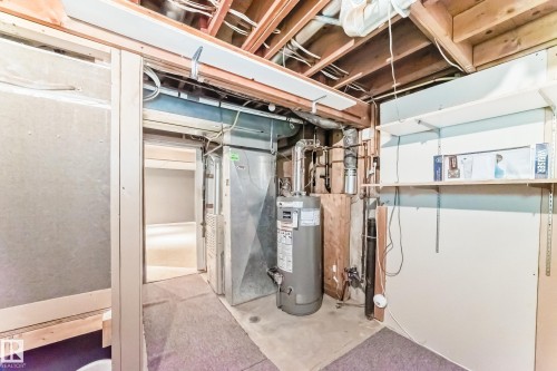 Utility area featuring a water heater, furnace, exposed ceiling joists, and open shelving - 9845 184 Street, Edmonton, AB - Indoor Photo Showing Basement