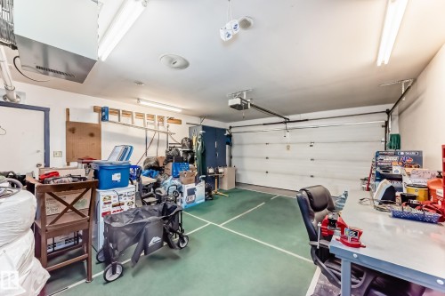 Garage space featuring a roll-up door, white walls, and a green floor with white markings - 9845 184 Street, Edmonton, AB - Indoor Photo Showing Garage