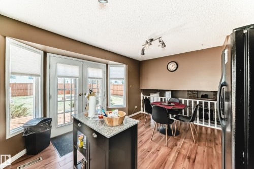 Kitchen area featuring wood-finish flooring, a freestanding island with a granite-style countertop, and French doors leading to exterior space - 9845 184 Street, Edmonton, AB - Indoor Photo Showing Dining Room