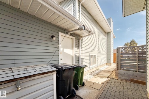 Exterior side entrance featuring light-colored siding, a white door, and an exterior light fixture - 9845 184 Street, Edmonton, AB - Outdoor With Exterior