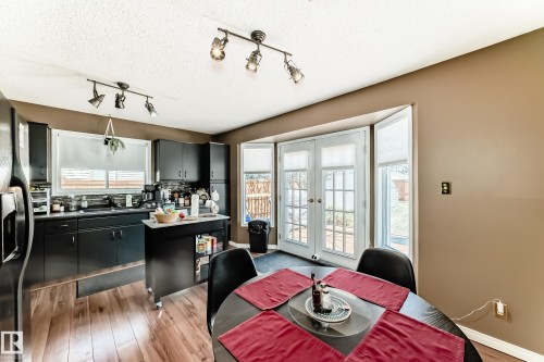 Kitchen featuring dark cabinetry, wood-finish flooring, and a subway tile backsplash - 9845 184 Street, Edmonton, AB - Indoor Photo Showing Dining Room