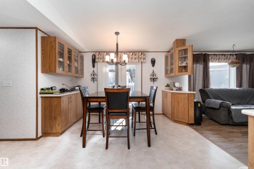 Open concept dining area featuring a dining table with chairs, an overhead chandelier, and built-in cabinetry with display features - 1663 Jubilee Crescent, Sherwood Park, AB - Indoor