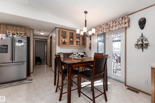 The dining area features a dark wood table and chairs, light-colored flooring, and a chandelier with multiple lights - 1663 Jubilee Crescent, Sherwood Park, AB - Indoor Photo Showing Dining Room