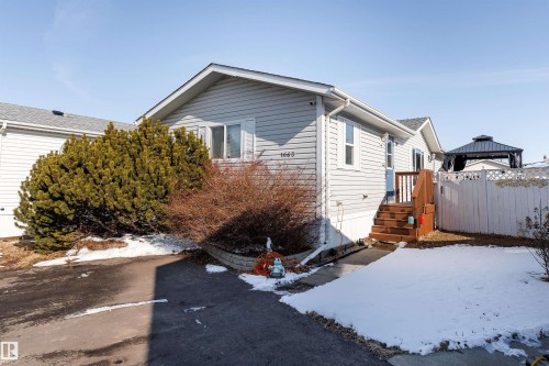 The property features a light-colored exterior with a front entry, wooden steps, and a compact front yard - 1663 Jubilee Crescent, Sherwood Park, AB - Outdoor