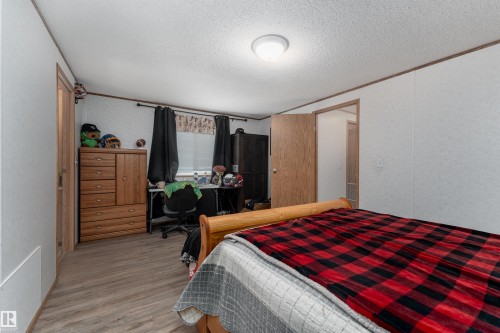 The interior features a wood-look floor, a window with dark curtains, and a ceiling light fixture - 1663 Jubilee Crescent, Sherwood Park, AB - Indoor Photo Showing Bedroom