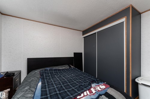 Bedroom featuring a dark-toned headboard and a built-in closet with sliding doors - 1663 Jubilee Crescent, Sherwood Park, AB - Indoor Photo Showing Bedroom