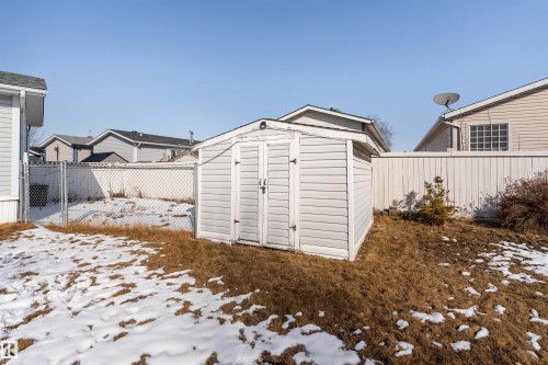 The property features a white outdoor storage shed with double doors, set within a fenced yard - 1663 Jubilee Crescent, Sherwood Park, AB - Outdoor