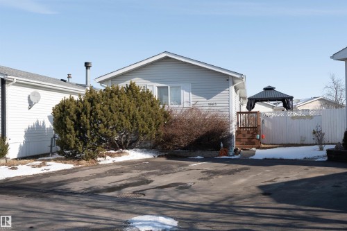 The property features a light-colored siding exterior, a driveway, and a fenced yard area - 1663 Jubilee Crescent, Sherwood Park, AB - Outdoor