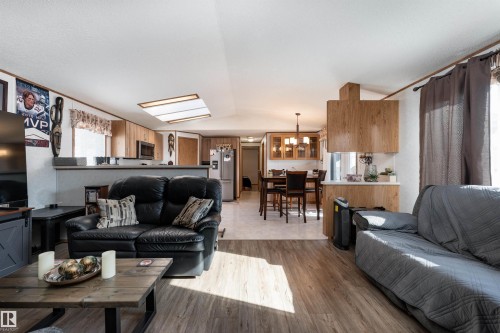 The living area features wood-look flooring and recessed lighting, with a view towards the dining area and kitchen - 1663 Jubilee Crescent, Sherwood Park, AB - Indoor Photo Showing Living Room
