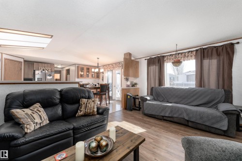 The living area features wood-look flooring and a window with curtains - 1663 Jubilee Crescent, Sherwood Park, AB - Indoor Photo Showing Living Room