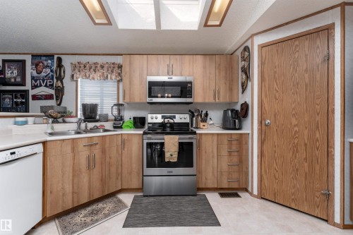 The kitchen features light wood cabinetry, stainless steel appliances, and a white countertop - 1663 Jubilee Crescent, Sherwood Park, AB - Indoor Photo Showing Kitchen With Double Sink