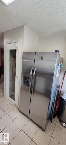 Kitchen with stainless steel side-by-side refrigerator, integrated water and ice dispenser, ceramic tile flooring, and a glass-paneled door - 14411 31 Street, Edmonton, AB -  Photo Showing Other Room