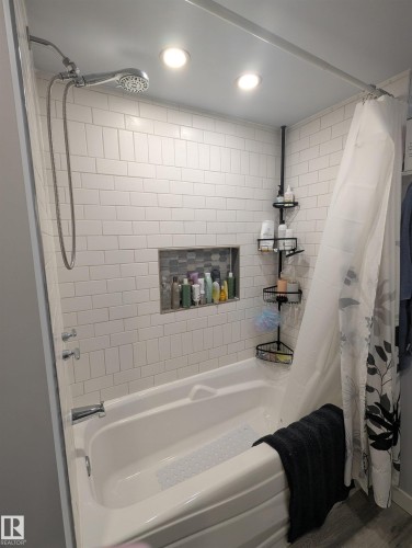 Bathroom featuring a bathtub with subway tile surround, a built-in shower niche, and recessed lighting - 2 9140 149 Street, Edmonton, AB - Indoor Photo Showing Bathroom