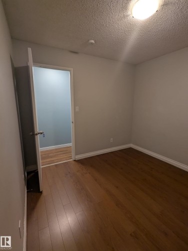 This room features rich brown flooring and neutral-toned walls - 2 9140 149 Street, Edmonton, AB - Indoor Photo Showing Other Room