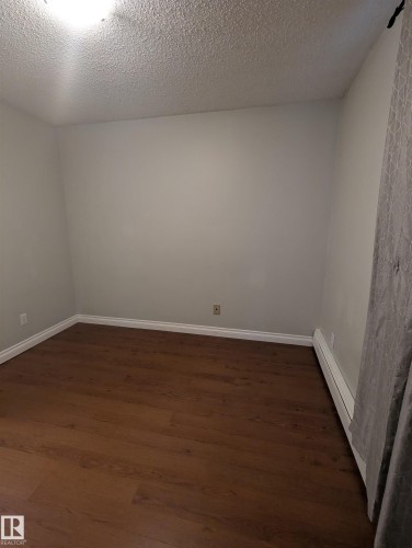 The room features warm-toned flooring, light-colored walls, and white baseboards - 2 9140 149 Street, Edmonton, AB - Indoor Photo Showing Other Room