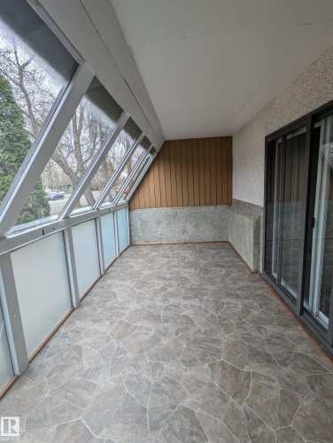 The property features an enclosed balcony with an angular glass wall, providing natural light - 2 9140 149 Street, Edmonton, AB - Indoor Photo Showing Other Room