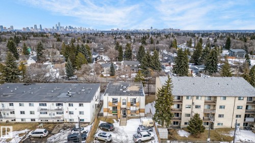 Aerial view of the property and surrounding neighborhood, featuring a treed landscape and distant city skyline - 2 9140 149 Street, Edmonton, AB - Outdoor