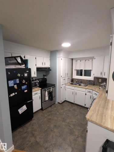 The kitchen features white cabinetry, stone-look countertops, and appliances including a refrigerator, stove, and microwave - 2 9140 149 Street, Edmonton, AB - Indoor Photo Showing Kitchen With Double Sink