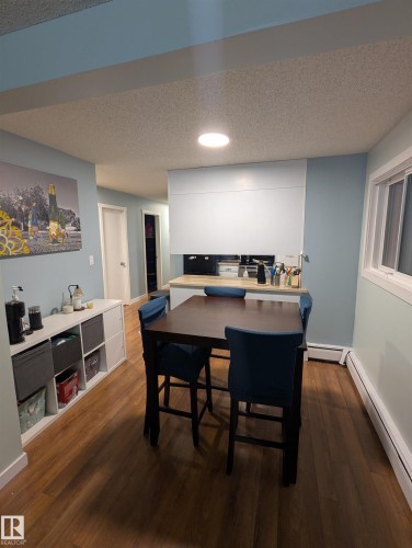 The dining area features engineered wood flooring, light blue walls, and a recessed ceiling light - 2 9140 149 Street, Edmonton, AB - Indoor