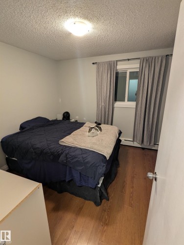 This room features wood-style flooring and a window with curtains - 2 9140 149 Street, Edmonton, AB - Indoor Photo Showing Bedroom