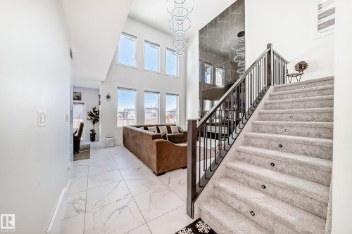 Grand foyer featuring a carpeted staircase with individual step lighting and dark wood-finish railing - 17459 80 Street, Edmonton, AB - Indoor Photo Showing Other Room