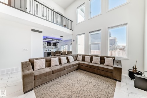 Two-story living area featuring a prominent upper-level balcony with metal railing, high ceilings, and a wall of tall windows - 17459 80 Street, Edmonton, AB - Indoor