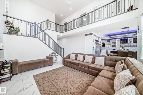 Two-story living area featuring a prominent staircase with dark metal railings, white walls, and large format white tile flooring - 17459 80 Street, Edmonton, AB - Indoor