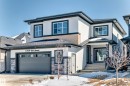 Contemporary stucco exterior featuring a covered entry, stone accents, dark trim, a two-car garage with frosted windows, and an asphalt shingle roof - 17459 80 Street, Edmonton, AB  - Outdoor With Facade 