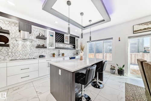 Open-concept kitchen featuring an oversized island with seating, a geometric tile backsplash, and a coffered ceiling with recessed lighting - 17459 80 Street, Edmonton, AB - Indoor Photo Showing Kitchen With Upgraded Kitchen
