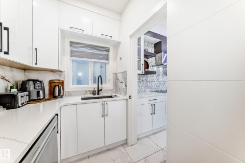 Modern kitchen featuring white cabinetry with black hardware, a black kitchen faucet, and a sleek sink - 17459 80 Street, Edmonton, AB - Indoor Photo Showing Kitchen
