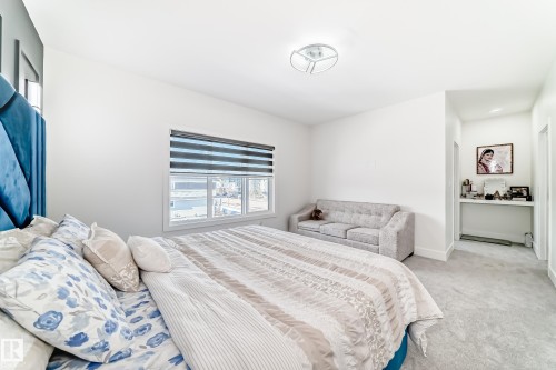 Spacious bedroom featuring light-colored carpeting, a multi-pane window with horizontal blinds, and a built-in alcove with a desk area - 17459 80 Street, Edmonton, AB - Indoor Photo Showing Bedroom