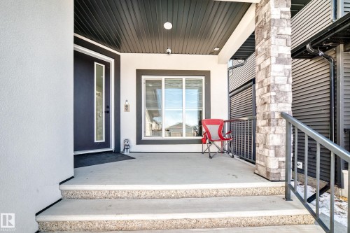 Inviting front entry featuring a dark-paneled door with vertical glass insert, stucco exterior, and a stone-clad column - 17459 80 Street, Edmonton, AB - Outdoor With Exterior