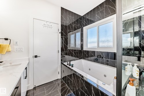 Built-in jetted tub with black-veined tile surround, dual pane window, and black fixtures - 17459 80 Street, Edmonton, AB - Indoor Photo Showing Bathroom