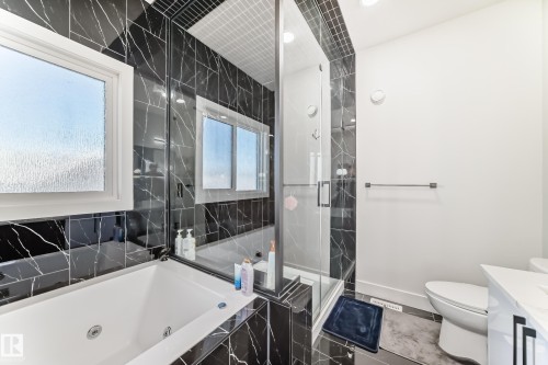 Bathroom featuring a jetted soaking tub, black marble-look tile surround, and a glass-enclosed shower with a black marble-look tile accent wall - 17459 80 Street, Edmonton, AB - Indoor Photo Showing Bathroom