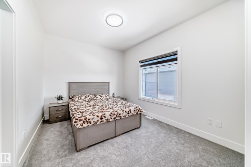 Bedroom featuring light gray carpeting, a large window with roller shades, white baseboards, and a flush-mount ceiling light fixture - 17459 80 Street, Edmonton, AB - Indoor Photo Showing Bedroom