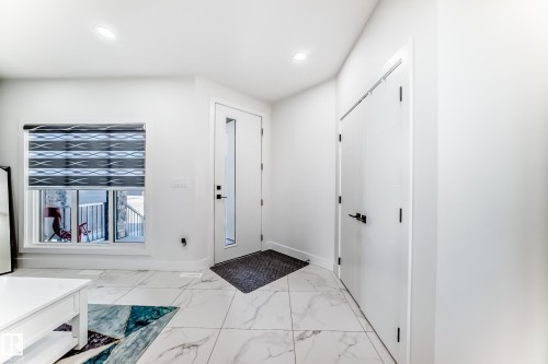 Entryway featuring large format marble-look tile flooring, a contemporary window with a privacy blind, and a modern door with an opaque glass insert - 17459 80 Street, Edmonton, AB - Indoor Photo Showing Other Room