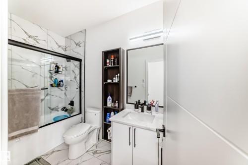 Contemporary bathroom featuring a white vanity with an integrated rectangular sink and dark-toned faucet, complemented by a large framed mirror - 17459 80 Street, Edmonton, AB - Indoor Photo Showing Bathroom