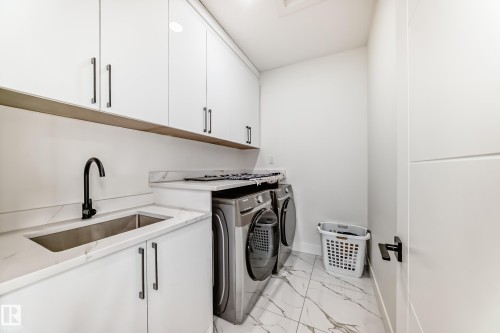 Dedicated laundry room featuring a built-in stainless steel sink, sleek white cabinetry, and patterned floor tiling - 17459 80 Street, Edmonton, AB - Indoor Photo Showing Laundry Room
