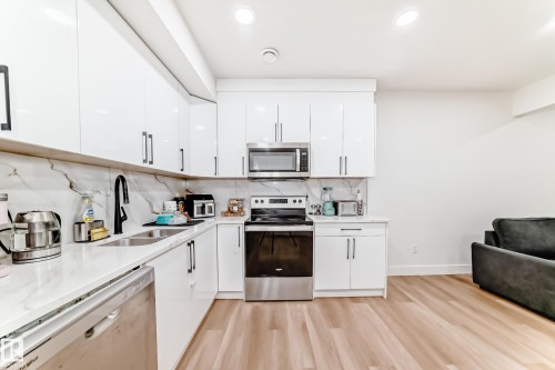 Contemporary kitchen featuring white flat-panel cabinetry, stainless steel appliances, and light wood-finish flooring - 17459 80 Street, Edmonton, AB - Indoor Photo Showing Kitchen With Double Sink