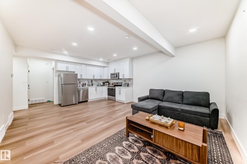 Open-concept living space featuring wood-finish flooring, a contemporary kitchen with white cabinetry, stainless steel appliances, recessed lighting, and white baseboards - 17459 80 Street, Edmonton, AB - Indoor Photo Showing Living Room