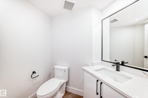 Bathroom featuring a white vanity with a rectangular undermount sink, quartz-finish countertop, matte black faucet, and a large frameless mirror - 17459 80 Street, Edmonton, AB - Indoor Photo Showing Bathroom