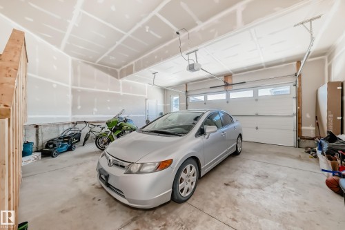 Spacious garage featuring a concrete floor, high ceilings, and a white overhead garage door with horizontal window inserts - 17459 80 Street, Edmonton, AB - Indoor Photo Showing Garage