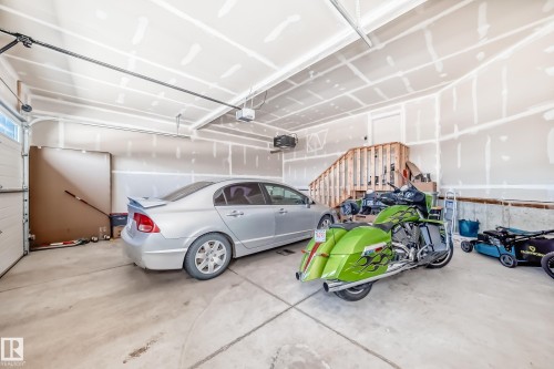 Spacious garage featuring a concrete floor, high ceilings, and an exposed wood staircase leading to an upper level - 17459 80 Street, Edmonton, AB - Indoor Photo Showing Garage
