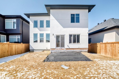 Contemporary white stucco exterior with a dark roofline, multiple windows, a sliding glass patio door, and a private wooden fence - 17459 80 Street, Edmonton, AB - Outdoor