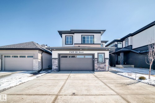 Contemporary exterior with a double garage door, stone accents, crisp white siding, dark trim, and a concrete driveway - 17459 80 Street, Edmonton, AB - Outdoor With Facade